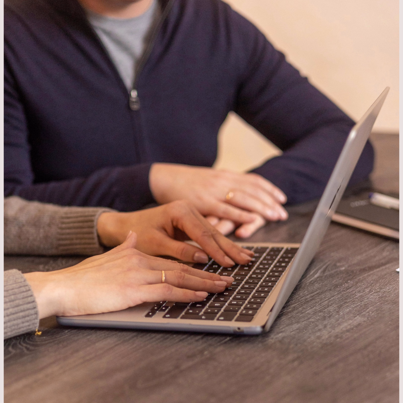 Eine Nahaufnahme von den Fingern einer Frau, die auf der Tastatur ihres Laptops liegen.